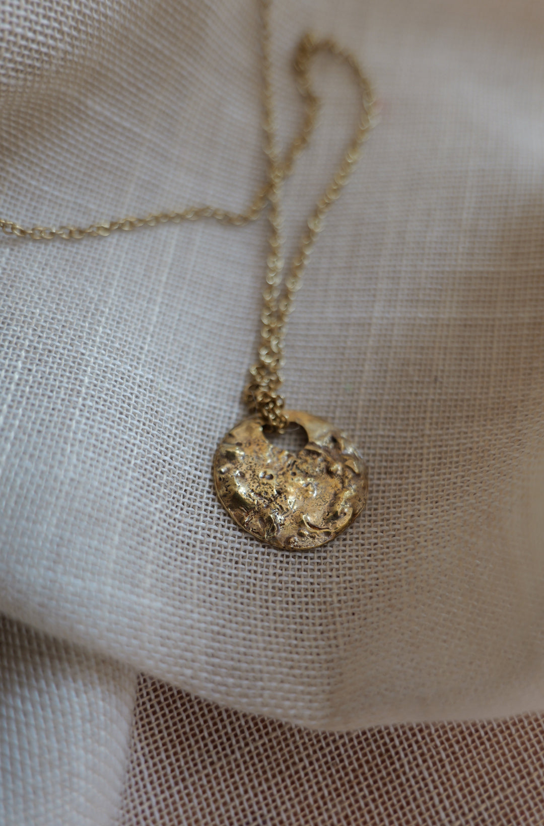 Handcrafted brass Moonscapes medallion necklace by Atelier Objectora, featuring an organic, molten-textured coin pendant inspired by the moon and the lunar landscapes. A raw yet elegant statement piece on a sturdy chain.
Ručne vyrobený mosadzný náhrdelník Moonscapes od Atelier Objectora s organickým, taveným povrchom medailónu inšpirovaným mesiacom a povrchom mesiaca. Surový, no elegantný šperk na pevnej retiazke.