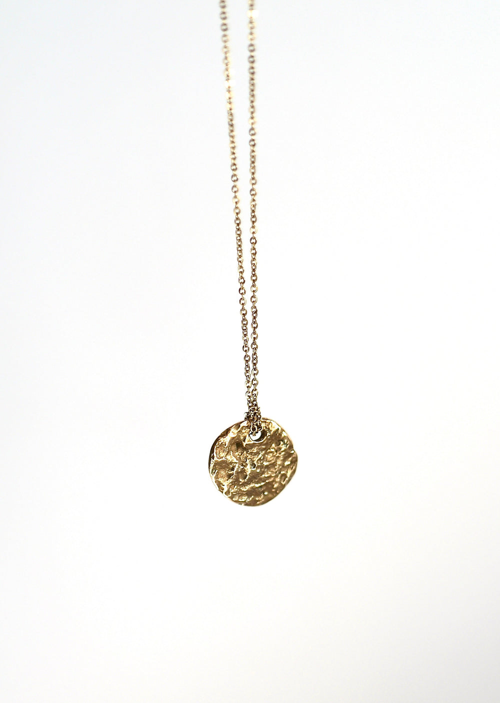Handcrafted bronze Moonscapes medallion necklace by Atelier Objectora, featuring an organic, molten-textured coin pendant inspired by the moon and the  lunar landscapes. A raw yet elegant statement piece on a sturdy chain.

Ručne vyrobený bronzový náhrdelník Moonscapes od Atelier Objectora s organickým, taveným povrchom medailónu inšpirovaným mesiacom a povrchom mesiaca. Surový, no elegantný šperk na pevnej retiazke.