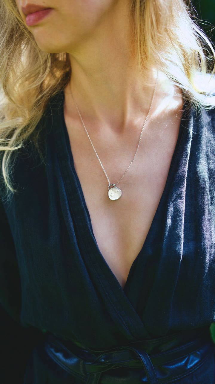 Ručne vyrobený medailón zo striebra rýdzosti 925/1000 je navrhnutý tak, aby v sebe uchoval niečo dôležité – kúsok vášho príbehu.

Povrch prívesku má organickú, nepravidelnú štruktúru a pridanú patinu. Každý kus získava v procese výroby inú jedinečnú textúru.

Do prívesku zalievam vašu fotografiu pomocou UV++ epoxidovej živice. Je trvácna, odolná, priehľadná a časom nežltne – vaša spomienka tak zostane jasná a chránená.