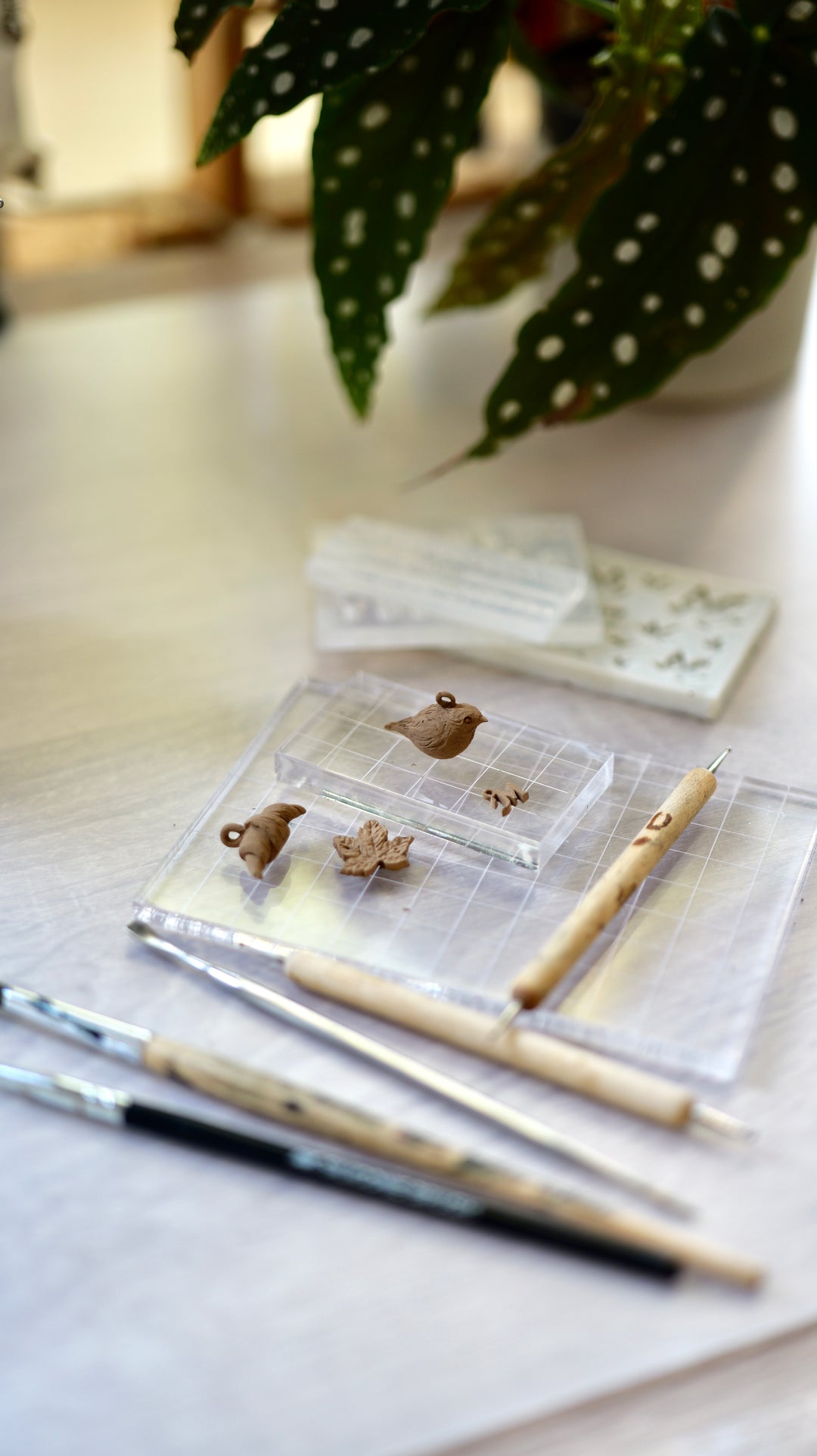 Detail na ukážku výrobkov z kurzu výroby šperkov z modelovacieho bronzu. Výrobky na podložke na bledom pozadí s modelovacími nástrojmi.