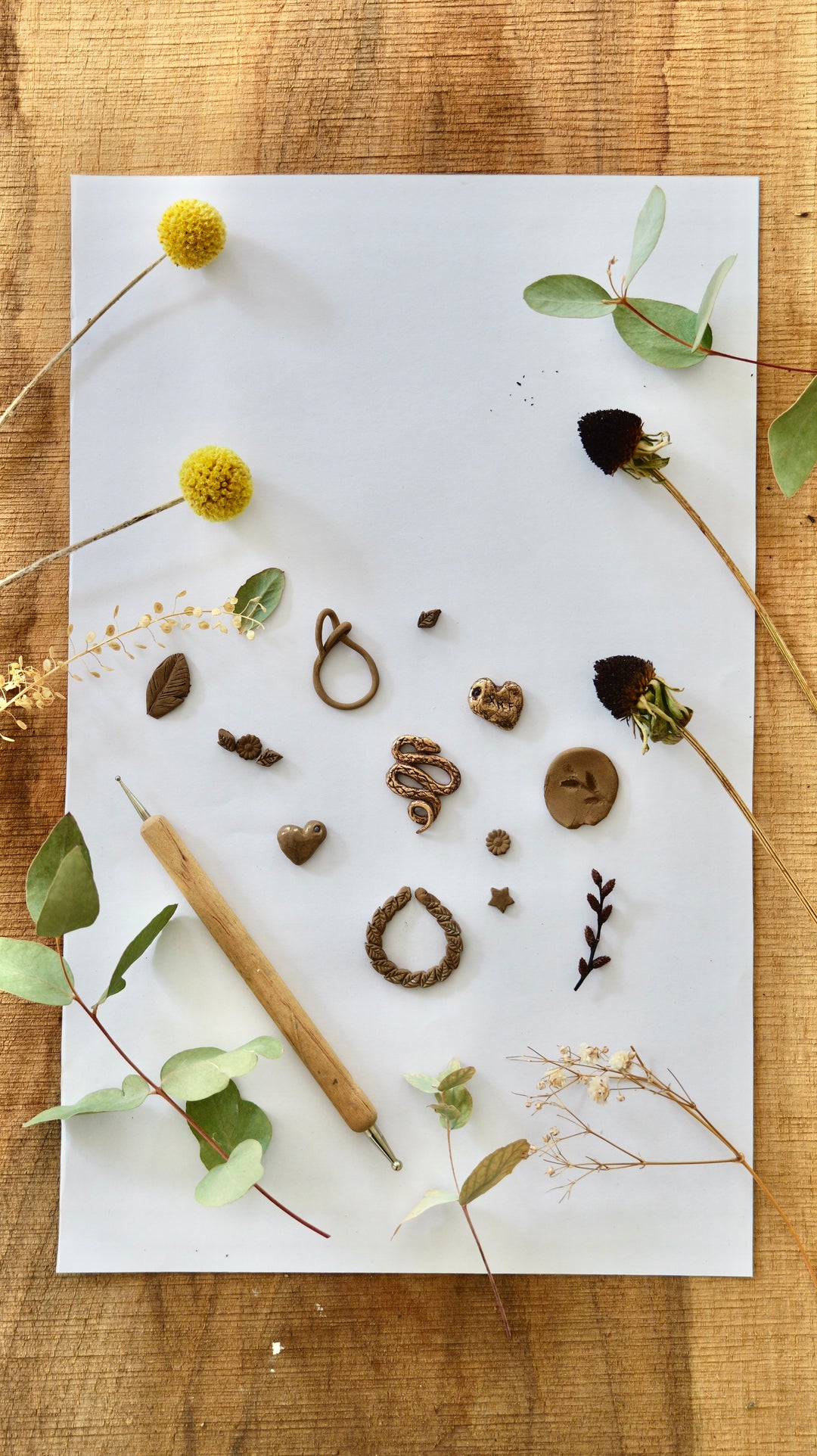 titulný obrázok pre kurzy výroby šperkov  bronze clay. Kúsky namodelovaných šperkov uložené na papiery s kúskami prírodnín.