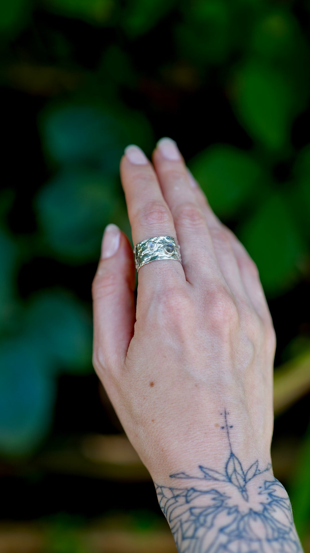 Výrazný široký prsteň zo striebra Ag 925/1000 s organickoou textúrou evokuje povrch vodnej hladiny, kde sa striebro prepletá do hladkých, vlnivých tvarov. Tento dizajn je doplnený o labradorit a mesačný kameň ktorého odlesky pripomínajú mystické hlbiny vody, akoby sa odrážali v pokojnej hladine.